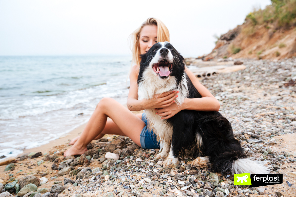 Mulher feliz abraçando o cachorro na praia
